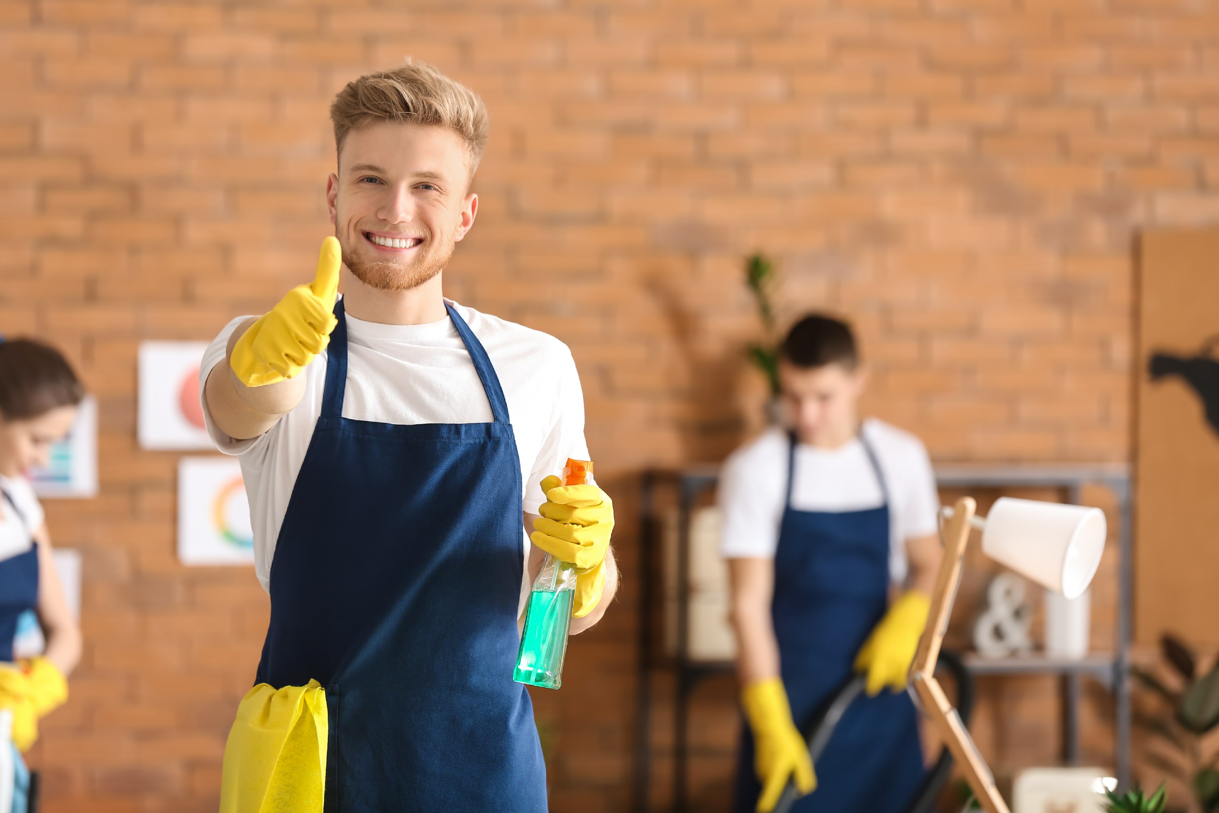 Male janitor showing thumb-up gesture in office during cleaning